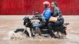 A motorcyclist rides with a passenger on a flooded United Nations Road in Dar es Salaam, on April 28, 2016. - The Tanzania Meteorological Agency says several days of heavy rain have been caused by remnants of tropical cyclone Fantala. (Photo by Daniel Hay