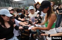Duo Lan, 31, founder of Beijing Girls Surfskating Community, distributes stickers with the community's logo to the members, during a free weekly training session in Beijing, China, June 18, 2022. (REUTERS/Tingshu Wang)