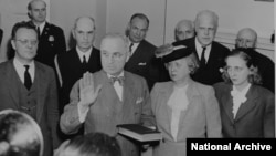 Bess and Margaret Truman stand beside Harry Truman as he takes the oath of office.