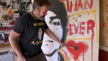 Photo of Manny Oliver smashing a painting with a hammer