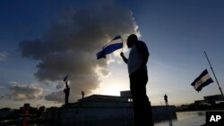 ARCHIVO - Las personas llevan banderas nacionales durante una protesta contra el gobierno con motivo del Día Nacional del Niño, en Managua, Nicaragua, el viernes 1 de junio de 2018.