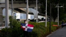 Yumi Kabaya, a fan of the Dominican Republic women's volleyball team, holds the country's flag to cheer for the team outside the Ariake Arena during the 2020 Summer Olympics, Thursday, July 29, 2021, in Tokyo, Japan. (AP Photo/Jae C. Hong)