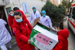 Doctors watch as donated medical supplies from Beijing are unloaded at a hospital in Wuhan in central China's Hubei Province, Thursday, Jan. 30, 2020. (Chinatopix via AP)