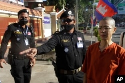 FILE: Court securities direct Cambodian-American lawyer Theary Seng, right, dressed in a prison-style orange outfit, to the entrance of Phnom Penh Municipal Court in Phnom Penh, Cambodia, Tuesday, Jan. 4, 2022
