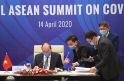 Vietnamese Prime Minister Nguyen Xuan Phuc, left, and his staff prepare documents ahead of the Special ASEAN summit on COVID-19 in Hanoi, Vietnam Tuesday, April 14, 2020.