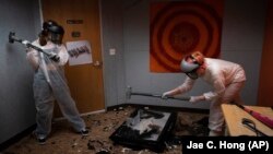 FILE - Two women use sledgehammers to destroy a TV in a rage room at Smash RX LLC in Westlake Village, Calif., Friday, Feb. 5, 2021. After a year in COVID-19 isolation, some people just want to grab a sledgehammer and smash everything in sight. (AP Photo/Jae C. Hong)