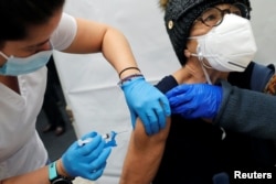 Seorang petugas kesehatan memberikan suntikan Vaksin Moderna COVID-19 kepada seorang wanita di sebuah lokasi vaksinasi selama pandemi COVID-19 di Manhattan di New York City, AS, 29 Januari 2021. (REUTERS/Mike Segar)