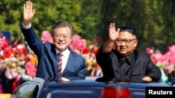 South Korean President Moon Jae-in and North Korean leader Kim Jong Un wave during a car parade in Pyongyang, North Korea, Sept. 18, 2018. 