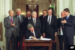 FILE - U.S. President Bill Clinton signs side deal of the three-nation North American Free Trade Agreement (NAFTA) at the White House, Washington, D.C., Tuesday, Sept. 14, 1993. (AP Photo/Ron Edmonds)