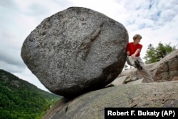 Doris Morgan, of Tampa, Fla., playfully attempts to dislodge the Bubble Rock near the summit of South Bubble Mountain, Friday, June 4, 2010, in Acadia National Park near Bar Harbor, Maine.