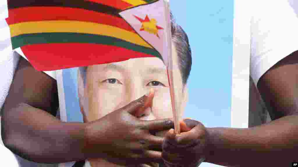 A woman holds a portrait of Chinese President Xi Jinping while welcoming him in Harare, Zimbabwe, Tuesday, Dec. 1, 2015. Jinping is in Zimbabwe for a two day State visit during which he is set to sign some bilateral agreements aimed at strengthening relationships between the two countries.