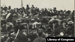 National Cemetery in Gettysburg, Penn., where President Abraham Lincoln gave his now famous speech, the Gettysburg Address. Lincoln is visible facing the crowd, not wearing a hat, about an inch below the third flag from the left. Josephine Cobb first found Lincoln's face while working with a glass plate negative at the National Archives in 1952. (Library of Congress)