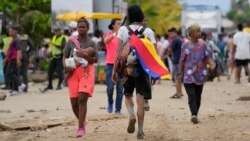 ARCHIVO - Un migrante porta una bandera venezolana en Necoclí, Colombia, un punto de parada para los migrantes que toman barcos a Acandi que conduce al Tapón del Darién, el jueves 13 de octubre de 2022.