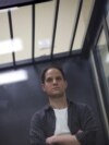 Evan Gershkovich, reportero del Wall Street Journal, detenido por cargos de espionaje, se encuentra detrás de una pared de vidrio de un recinto para los acusados antes de una audiencia judicial en Moscú, Rusia, el 23 de abril de 2024. 