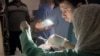 Doctors treat an injured man using mobile phone flashlight in Gaza