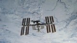 In this NASA photo, backdropped against clouds over Earth, the International Space Station is seen from Space Shuttle Discovery as the two orbital spacecraft accomplish their relative separation on March 7, 2011. (NASA via AP)