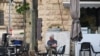 2024年4月14日，一名男子在耶路撒冷的一家路边咖啡馆一边喝早餐的饮料一边看书。