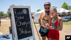 Festivalgoers use the free solar charging station at the Bonnaroo Music and Arts Festival on Saturday, June 18, 2022, in Manchester, Tenn. (Photo by Amy Harris/Invision/AP)