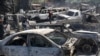 Varias personas buscan piezas rescatables de coches quemados en un taller mecánico incendiado durante la violencia desatada por pandillas armadas en Puerto Príncipe, Haití, el lunes 25 de marzo de 2024. 