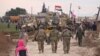In this frame grab from video, Russian, Syrian and others gather next to an American military convoy stuck in the village of Khirbet Ammu, east of Qamishli city, Syria, Feb. 12, 2020. 