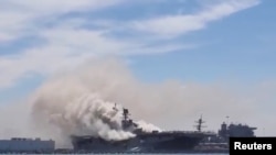 Asap mengepul dari kebakaran di kapal serbu amfibi Angkatan Laut AS USS Bonhomme Richard di Pangkalan Angkatan Laut San Diego, California, pada 12 Juli 2020. Video kebakaran ini secara keliru dikaitkan dengan serangan Houthi di Laut Merah.