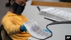 FILE - A county election worker scans mail-in ballots at a tabulating area at the Clark County Election Department, Nov. 5, 2020, in Las Vegas. 