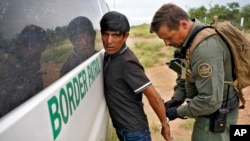 Агент Пограничного патруля США задерживает мигранта на границе с Мексикой.