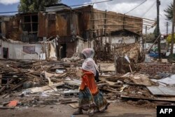 FILE—A woman walks past debris from houses during a planned demolition in the historical Piazza neighborhood of Addis Ababa on March 14, 2024.