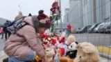 Một đứa trẻ đặt một món đồ chơi ở hàng rào cạnh nhà hát Crocus City Hall, ở rìa phía tây của Moscow, Nga, hôm Thứ Bảy, ngày 23 tháng 3 năm 2024, để tưởng nhớ các nạn nhân vụ xả súng hôm thứ Sáu mà nhóm Nhà nước Hồi giáo đã nhận trách nhiệm.