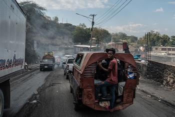 A man hangs onto the back of a bus in the troubled Delmas neighbourhood of Port-au-Prince.