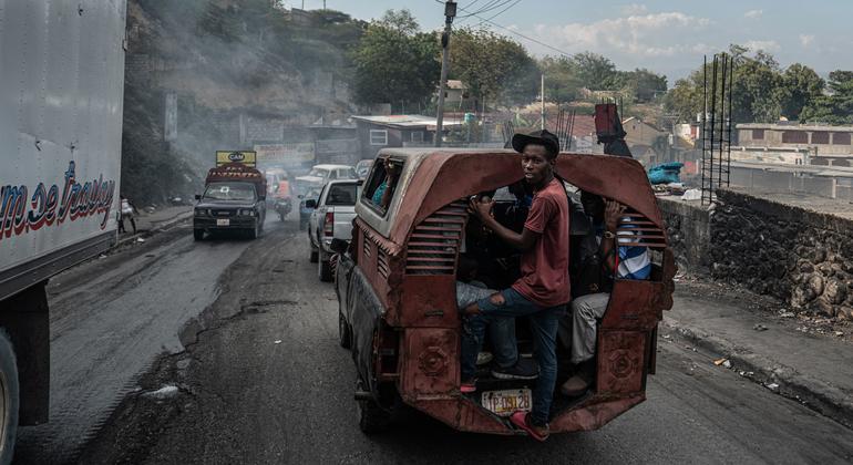 Un homme s'accroche à l'arrière d'un bus dans le quartier de Delmas, à Port-au-Prince.