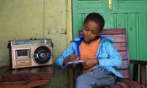 A young boy in Ethiopia attends class at home, taking lessons via the radio, which are being broadcast across the country. 