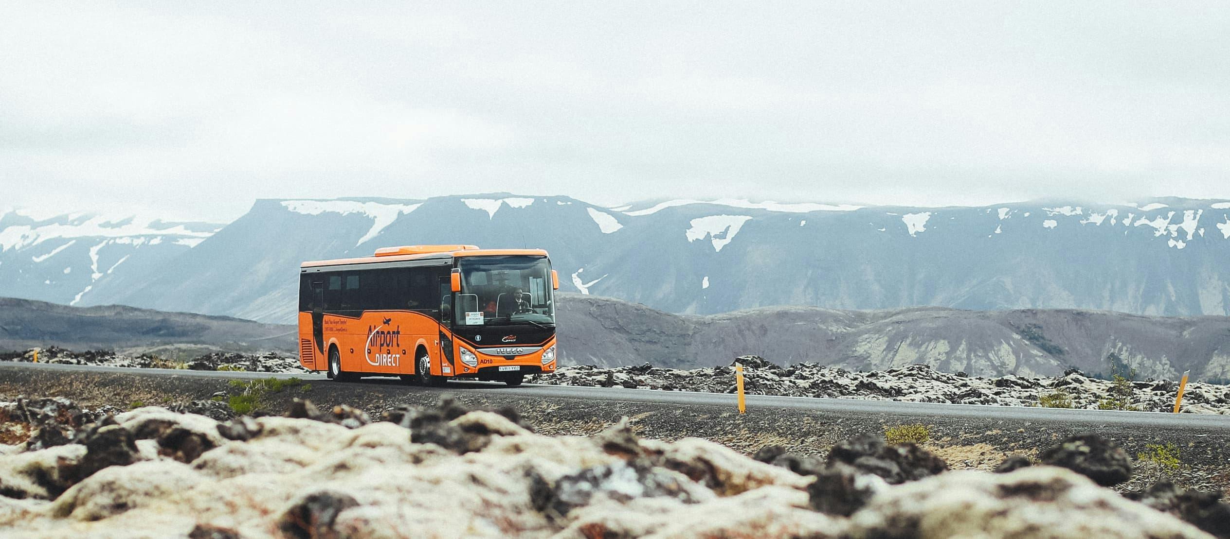 The Airport Direct transfer bus travels from Keflavik Airport to Reykjavik with snow sprinkled on the surrounding Reykjanes peninsula landscape.
