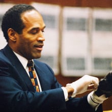 O.J. Simpson tries on a leather glove allegedly used in the murders of Nicole Brown Simpson and Ronald Goldman during testimony in Simpson's murder trial on June 15, 1995 in Los Angeles