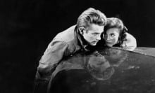 James Dean and Natalie Wood huddle together on the bonnet of a car in the film "Rebel Without a Cause".