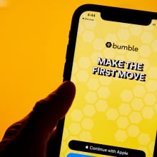 bumble app with yellow background and MAKE THE FIRST MOVE text displayed on iphone in front of orange background