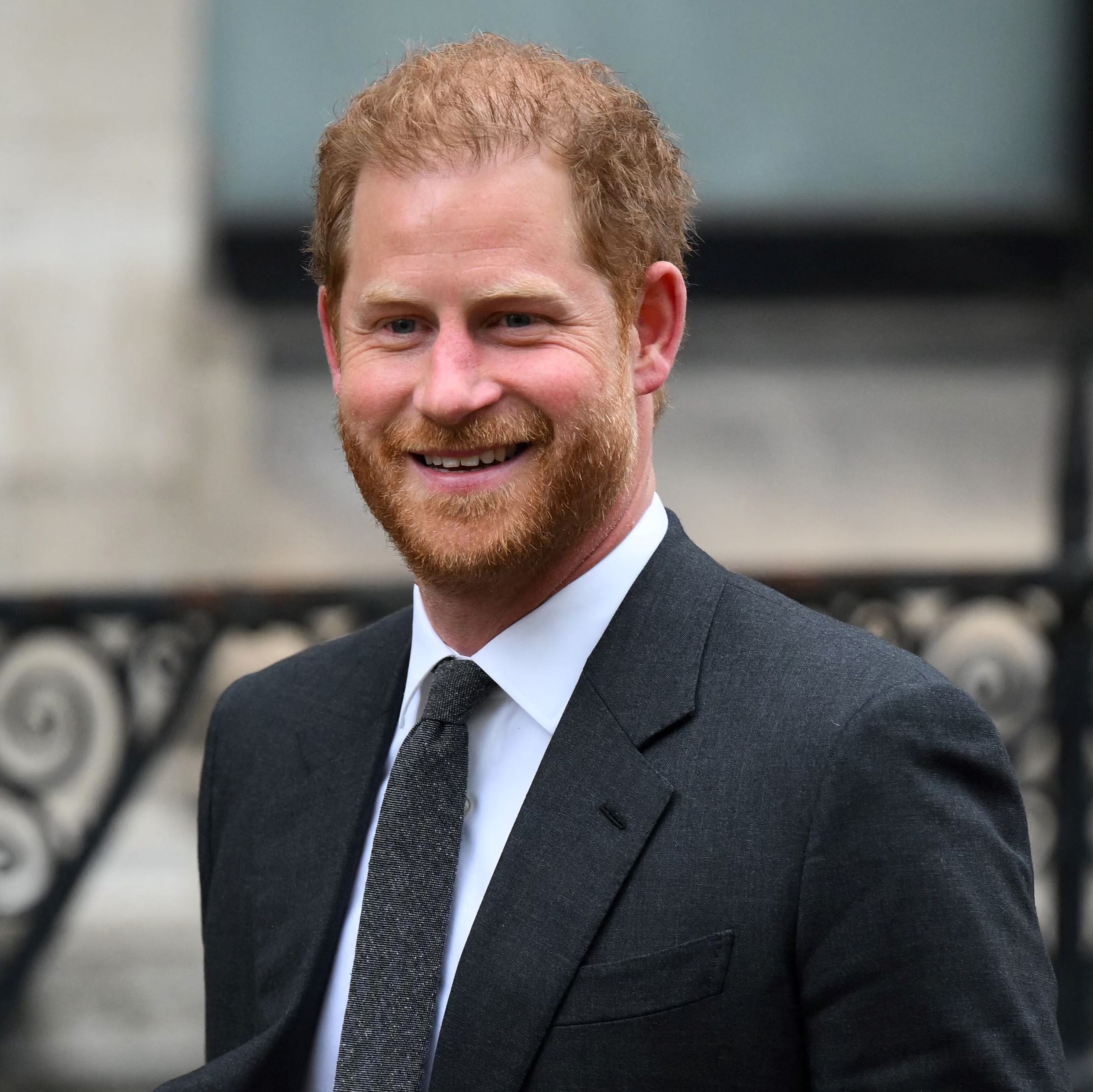 prince harry smiling for photographers as he walks into court