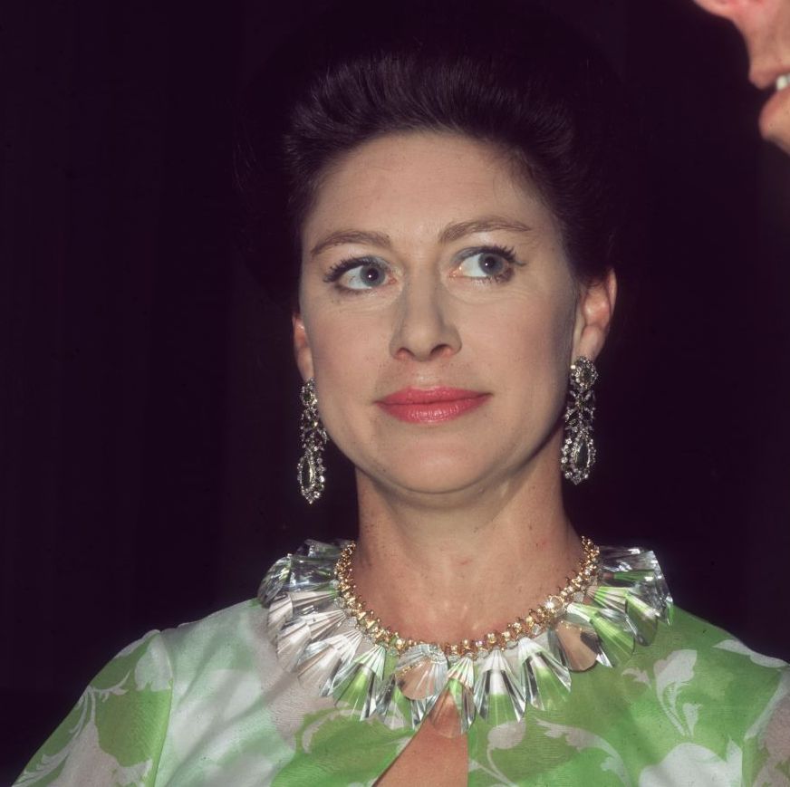 princess margaret looks to the right, she wears large dangling earrings, a matching large necklace and a green and white top