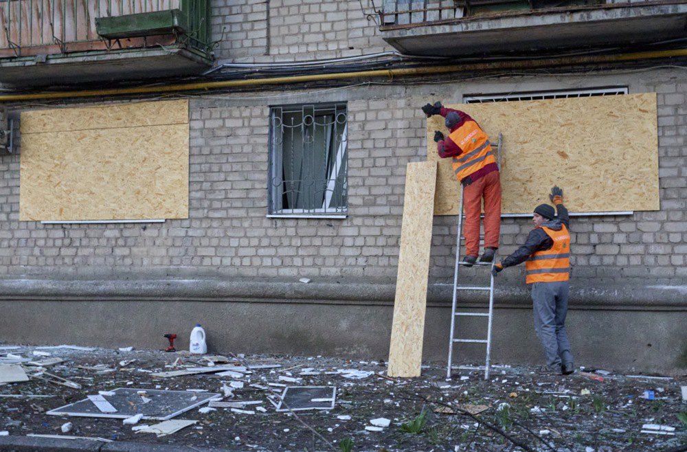 Комунальники забивають дошками вікна на місці обстрілу житлових будинків у Харкові, 27 березня 2024 р.