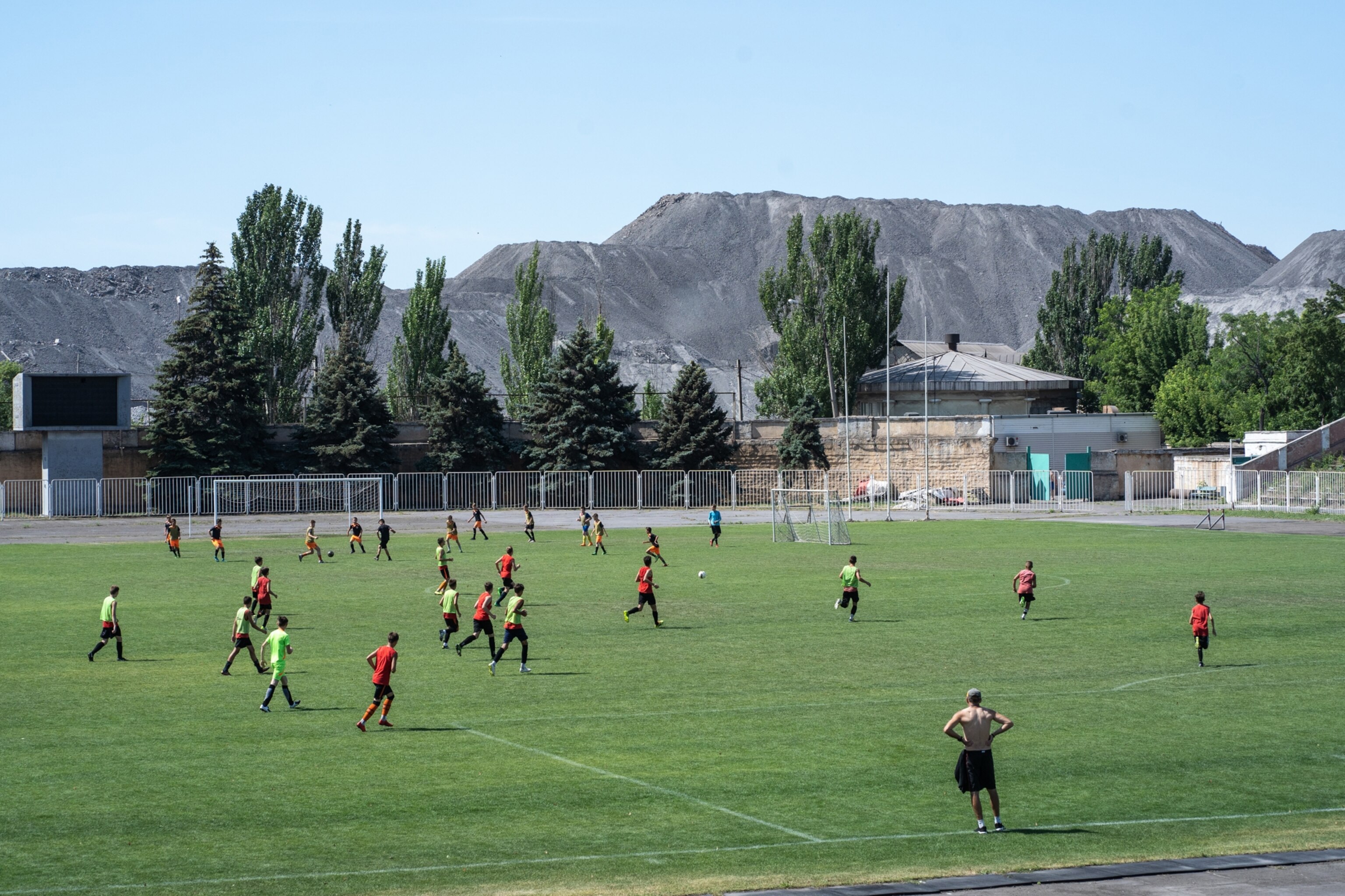 a soccer team plays in a field with a looming slagheap right behind the field