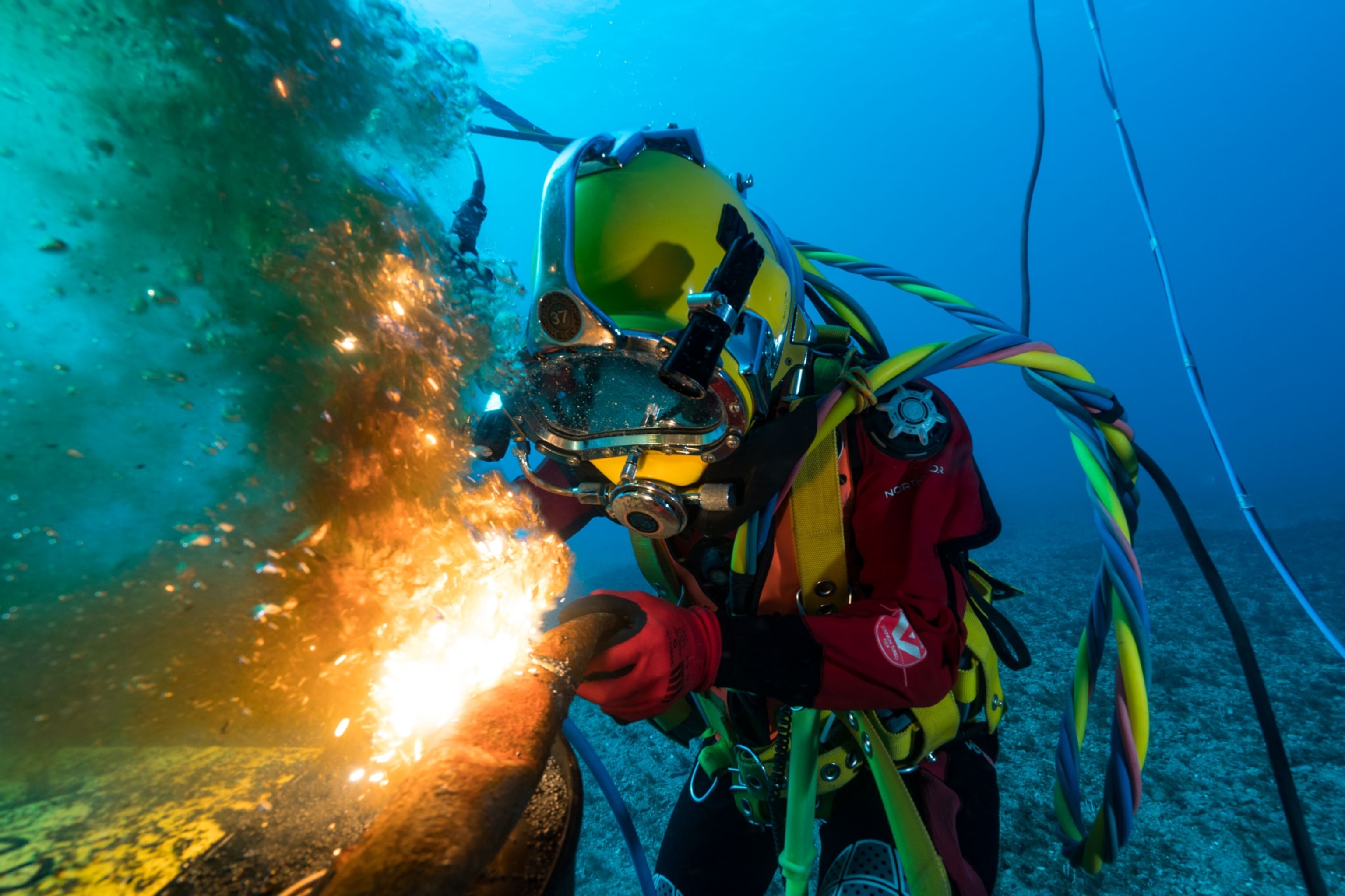 a person in a scuba suit underwater welding a pipe