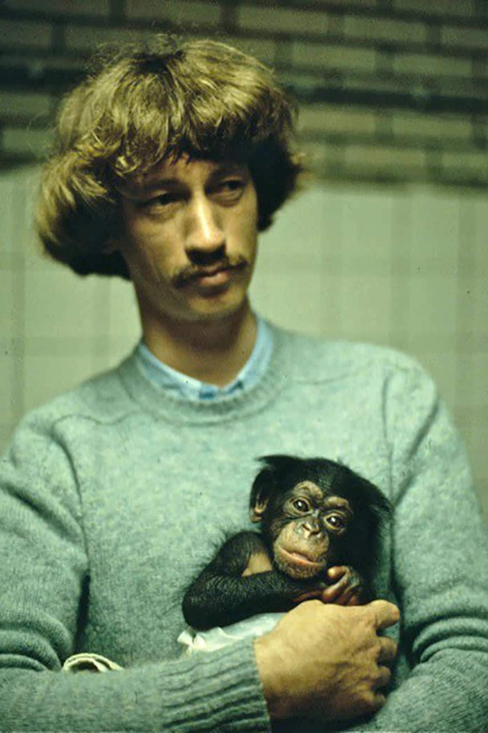 Picture of a young Frans de Waal holding a baby chimp in his arms.