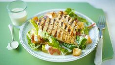 grilled chicken and lettuce salad on a plate with a glass of milk