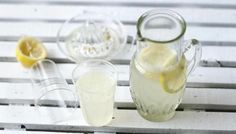 a pitcher filled with lemonade sitting on top of a table next to two glasses