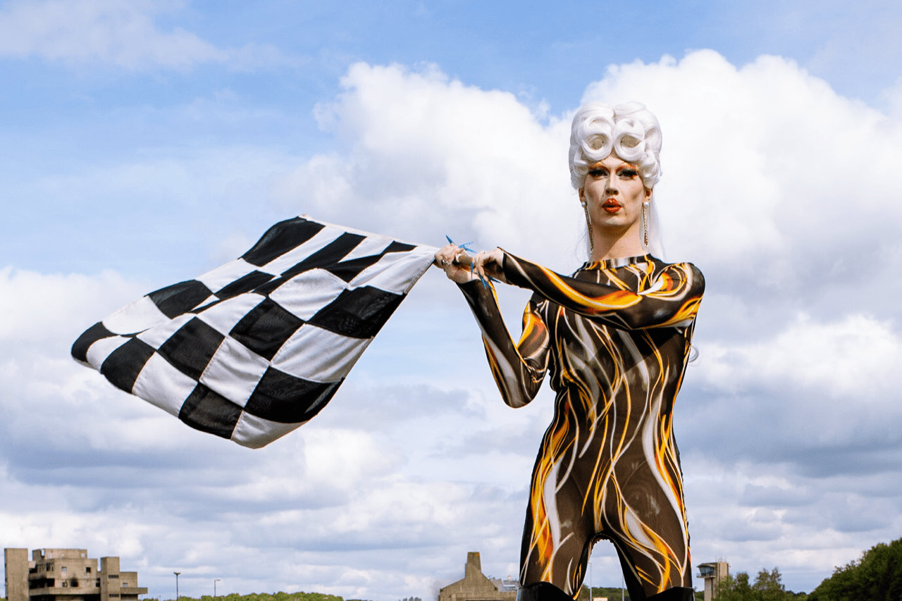 Performer wearing fiery skin tight costume waving a checkered racing flag