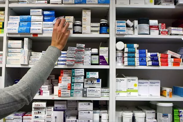 a pharmacist stocks shelves at a chemist.