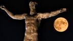 The moon rises above the statue of the ancient Greek god Poseidon in Ancient Corinth near in Athens on August 11, 2022.
