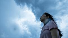 A woman looking up at storm clouds