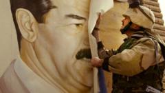 Американский слодат срывает плакат с Саддамом Хусейном