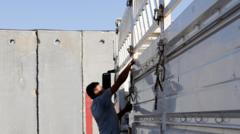 Грузовик с гуманитарной помощью у бетонного забора на въезде в Газу